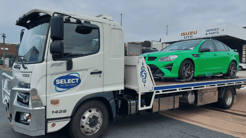 A Holden car being transported by tow truck.