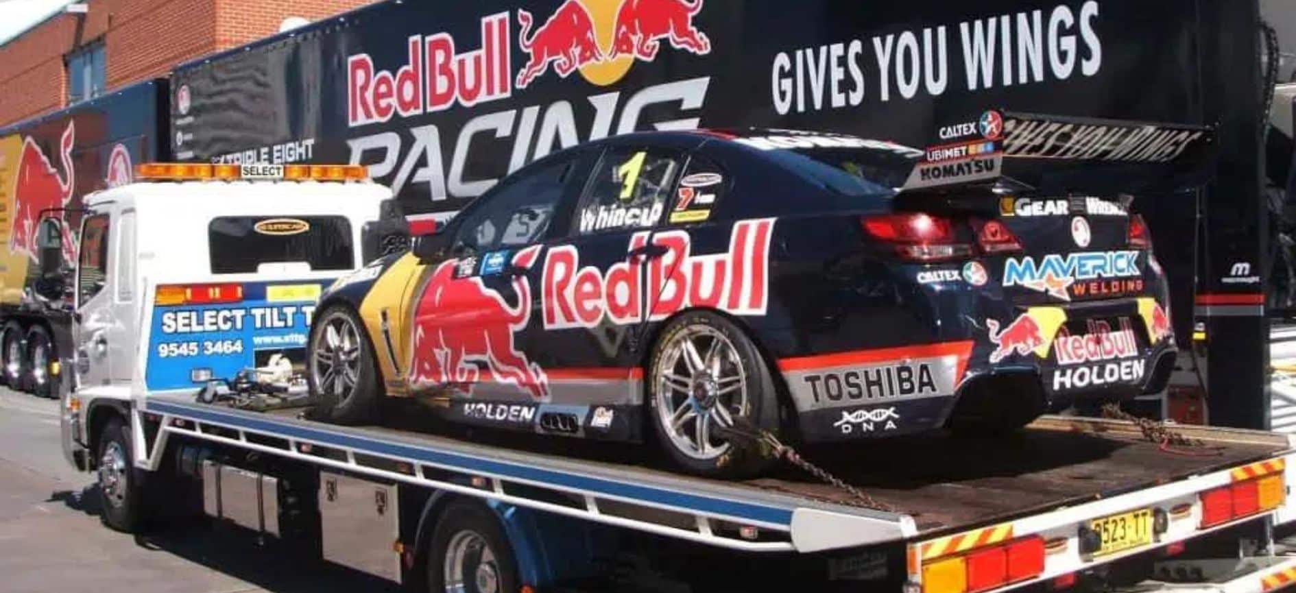 A Holden race car being delivered interstate by a reliable transport truck