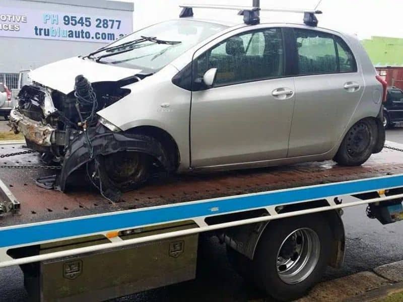 A car on flatbed tow truck receiving a breakdown towing service