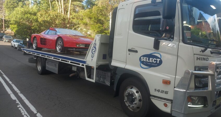 A Ferrari Testarossa being towed on a flat bed tow truck