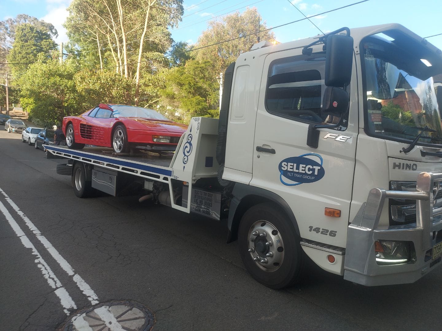 A Ferrari Testarossa being towed on a flat bed tow truck
