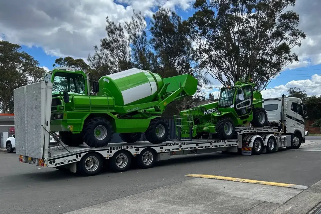 A prime mover transporting heavy machinery on a flatbed trailer