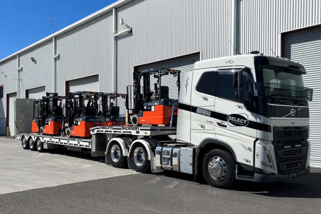 A prime mover transporting heavy machinery on a flat bed trailer