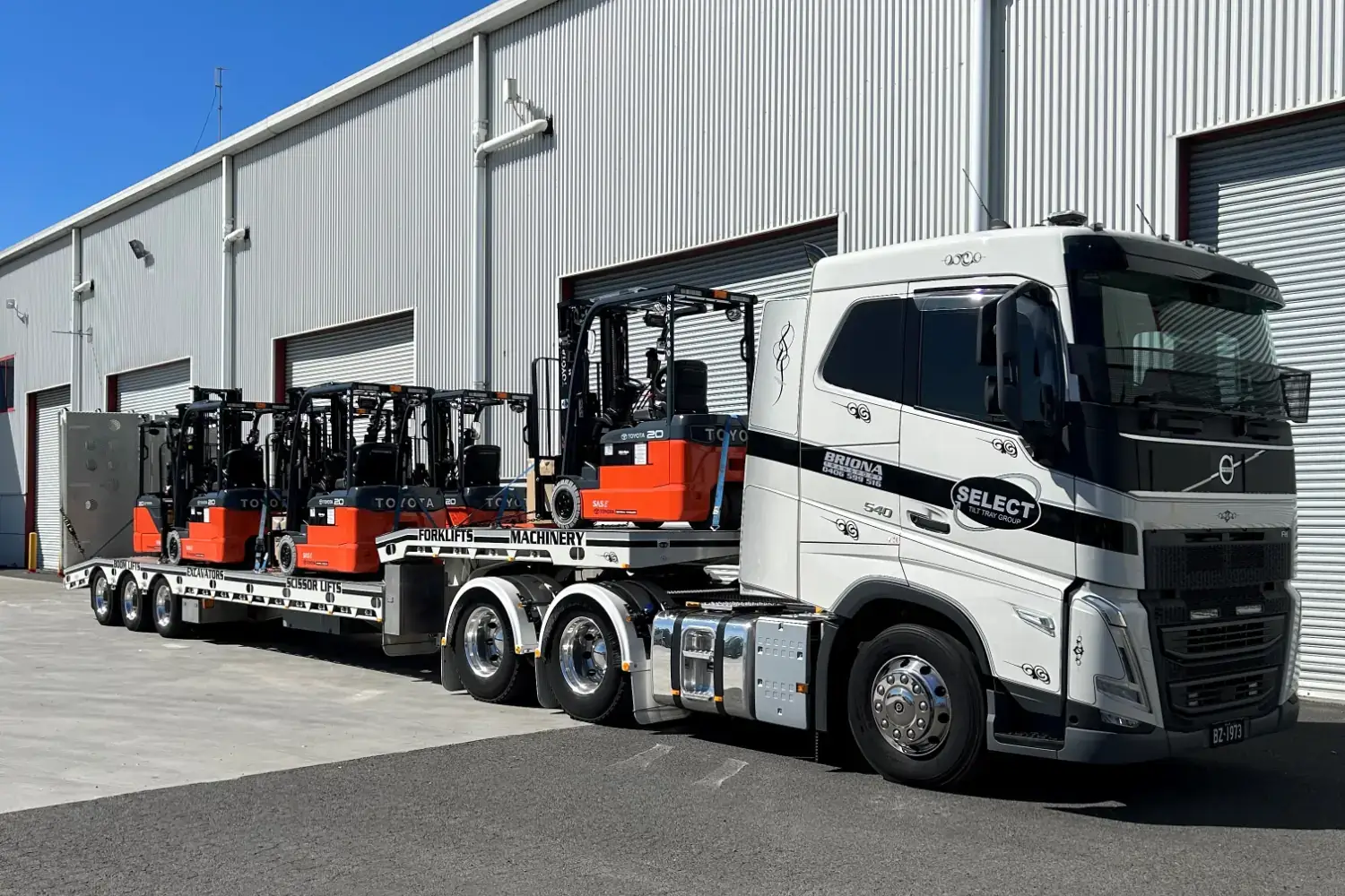 A prime mover towing heavy machinery on a flat bed trailer