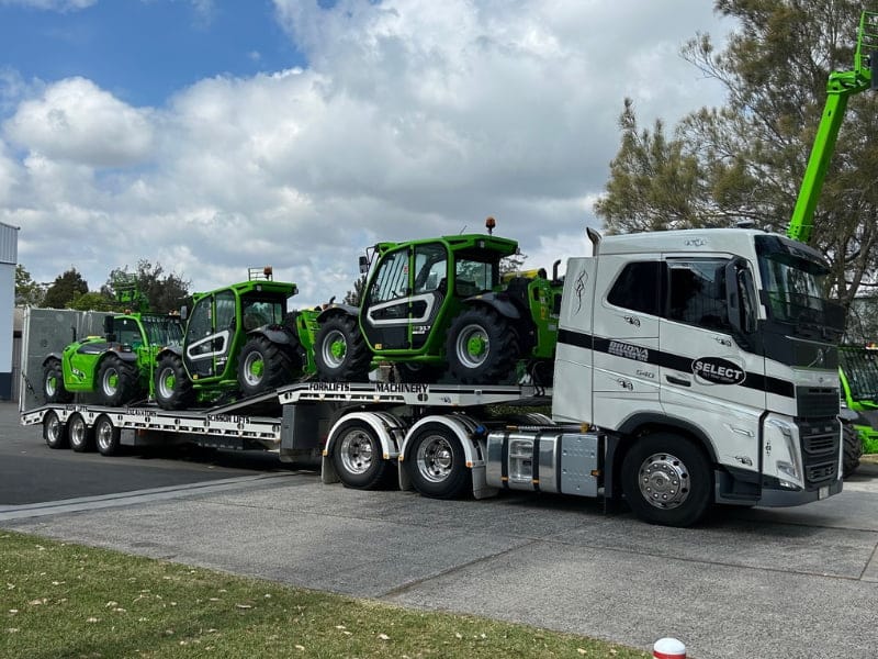Truck towing two heavy vehicles and machinery