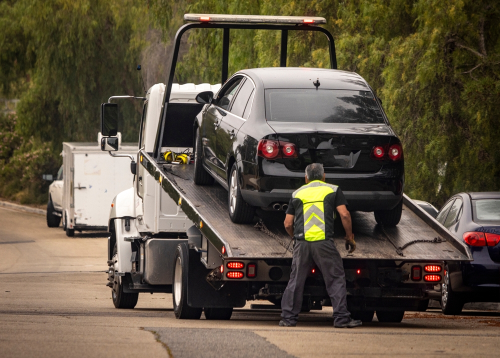 Tow truck driver securing a car onto a flatbed.