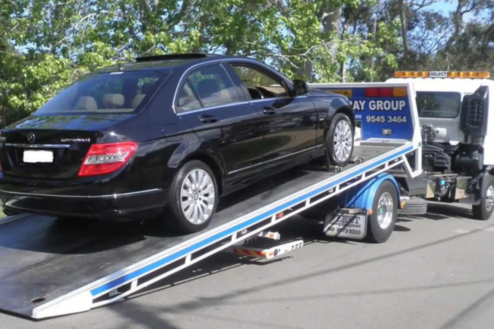 Car loaded onto a tilt tray tow truck.