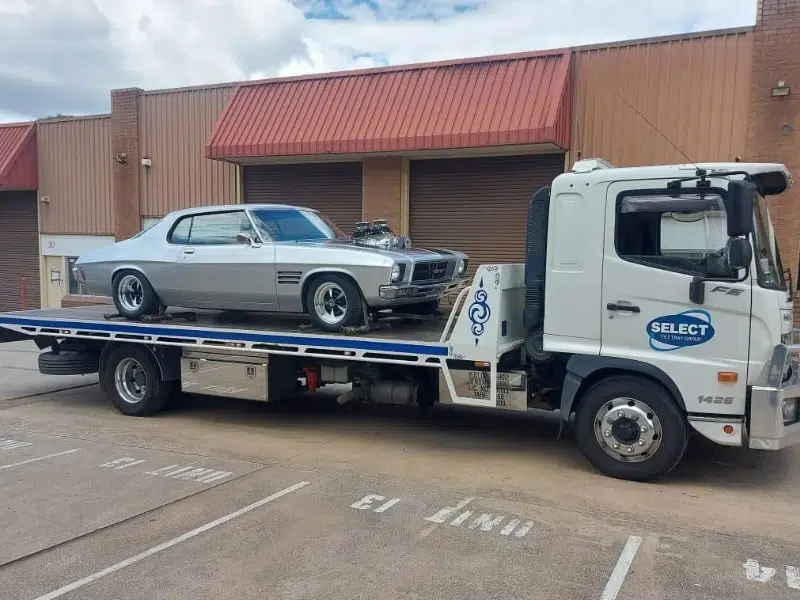 Classic Shelby Mustang secured on a tilt tray tow truck.