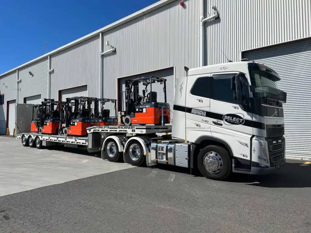 Forklifts carried on a tilt tray tow truck.